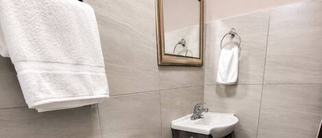 Egy modern fürőszoba, amelyben WC, mosdókagyló és tükör található.
