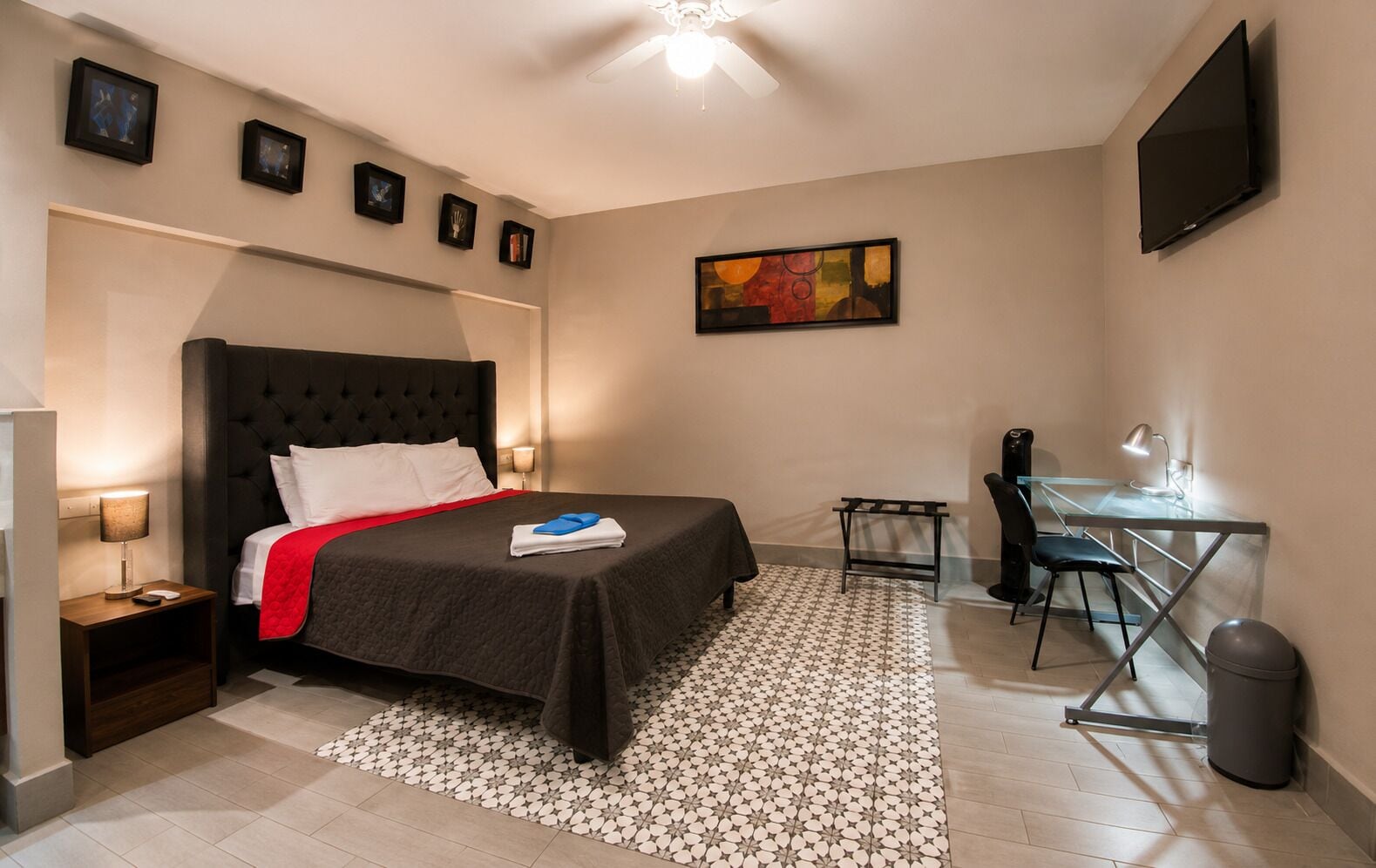 Habitación de hotel con cama, escritorio, silla y televisión.