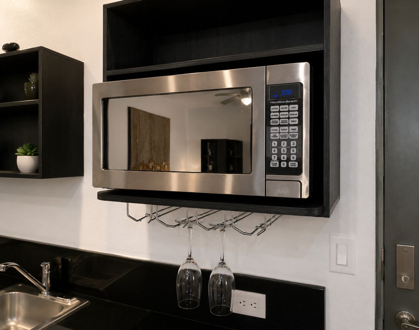 Une cuisine moderne équipée d’un four à micro-ondes encastré, d’un meuble à vin et d’un évier en acier inoxydable.