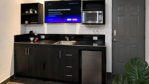 A modern kitchen with a built-in microwave, a coffee machine, and a flat-screen TV displaying a Netflix interface. - Barrio Inn Morelos (Monterrey)