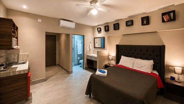 A hotel room with a bed, a desk, a bathroom, and a ceiling fan. - Barrio Inn Morelos (Monterrey)