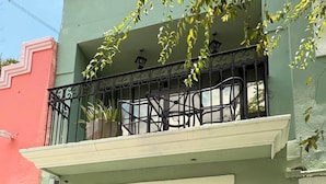 A building with a green facade, a black ornate gate, and a balcony with potted plants. - Barrio Inn Morelos (Monterrey)
