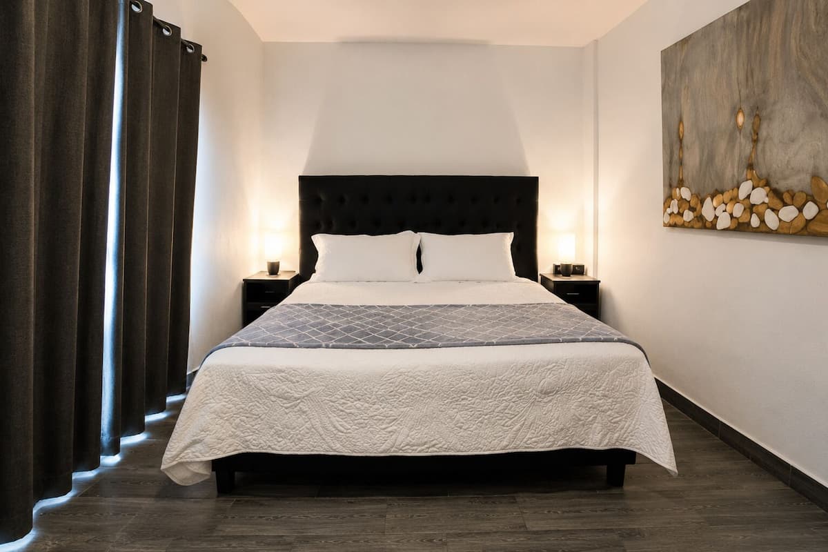 A neatly made bed with a quilted headboard, two bedside tables with lamps, and a wall art piece.