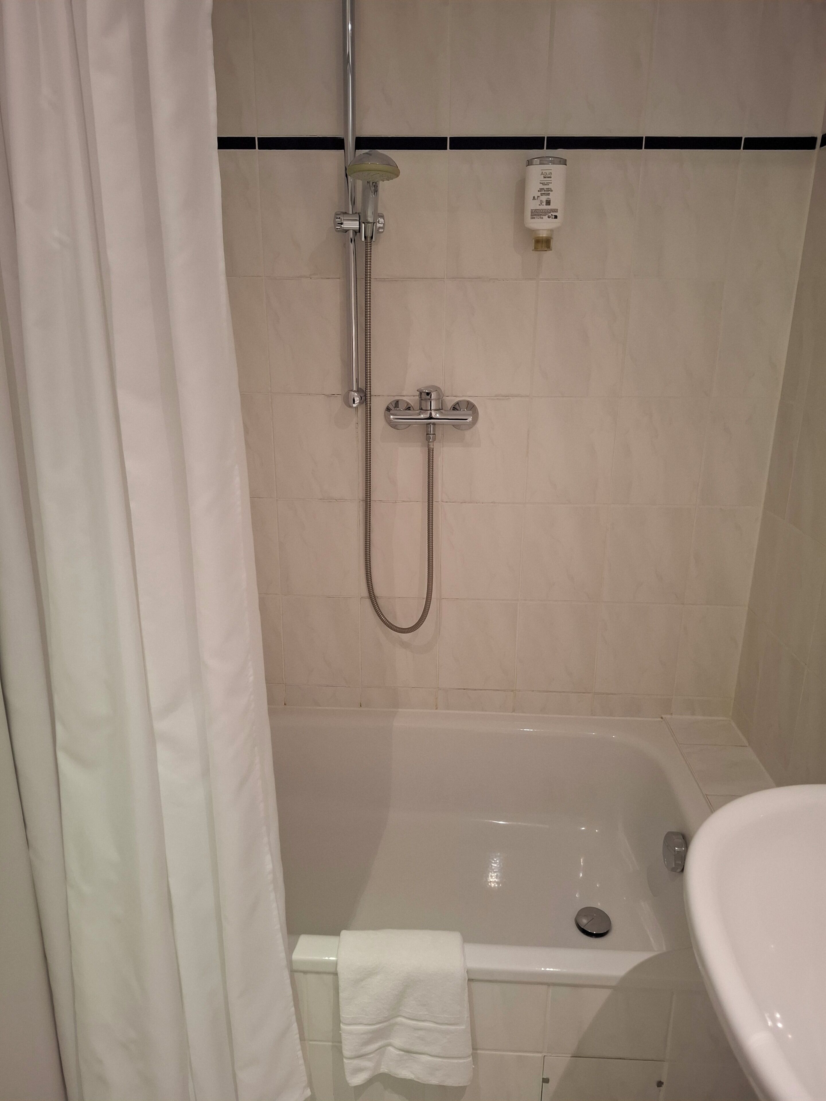 A bathroom with a bathtub, a showerhead, and a toilet.