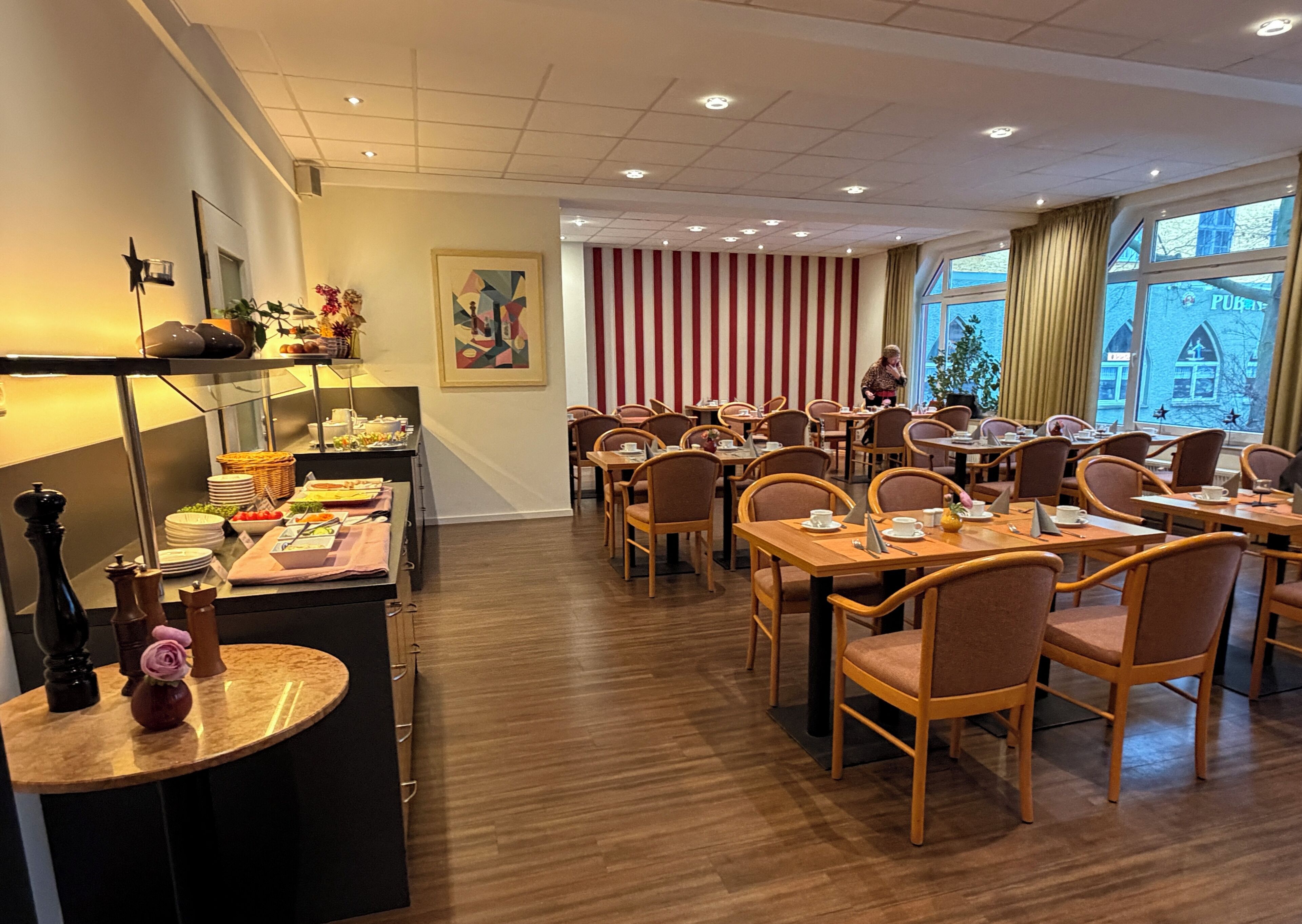 Un comedor de hotel con mesas, sillas y un mostrador tipo buffet.