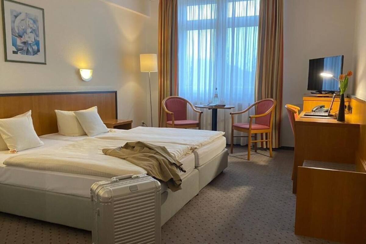 Une chambre d’hôtel équipée d’un lit, d’un bureau, d’une chaise, d’une télévision et d’une fenêtre avec des rideaux.