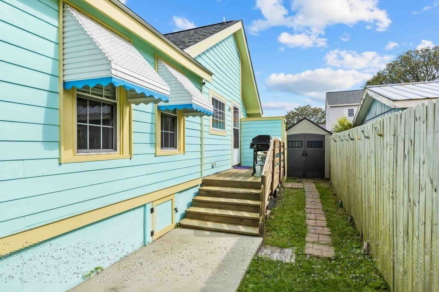 A two-story house with a visible staircase leading to the front door, a fenced yard, and a garage.