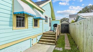 A two-story house with a visible staircase leading to the front door, a fenced yard, and a garage.