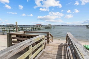 A wooden pier extending into calm waters, with a clear sky and distant structures. - The Mermaid Cottage - Walk to Waterfront (Morehead City)