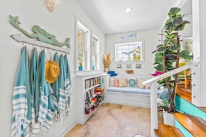 A cozy interior with a staircase, a bookshelf, and a window with a view. - The Mermaid Cottage - Walk to Waterfront (Morehead City)