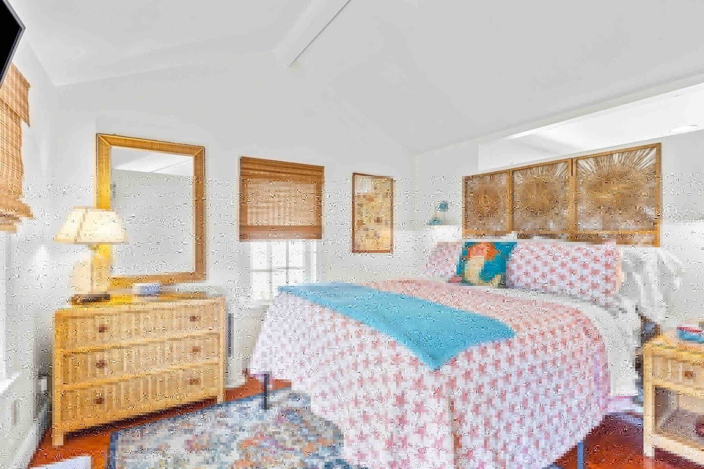 A bedroom with a bed, dresser, mirror, and window.