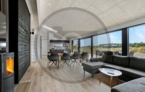 A modern interior with a dining area, sofa, and large windows offering a view of the outdoors. - Awesome home in Jerup with sauna (Jerup)
