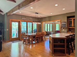 A spacious dining area with wooden furniture, large windows, and a view of the outdoors.