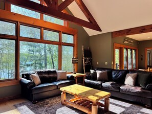 A spacious living room with large windows, a wooden coffee table, and two sofas.