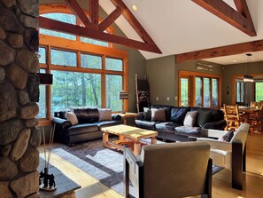 A spacious living area with a stone wall, large windows, and a dining area with wooden furniture.