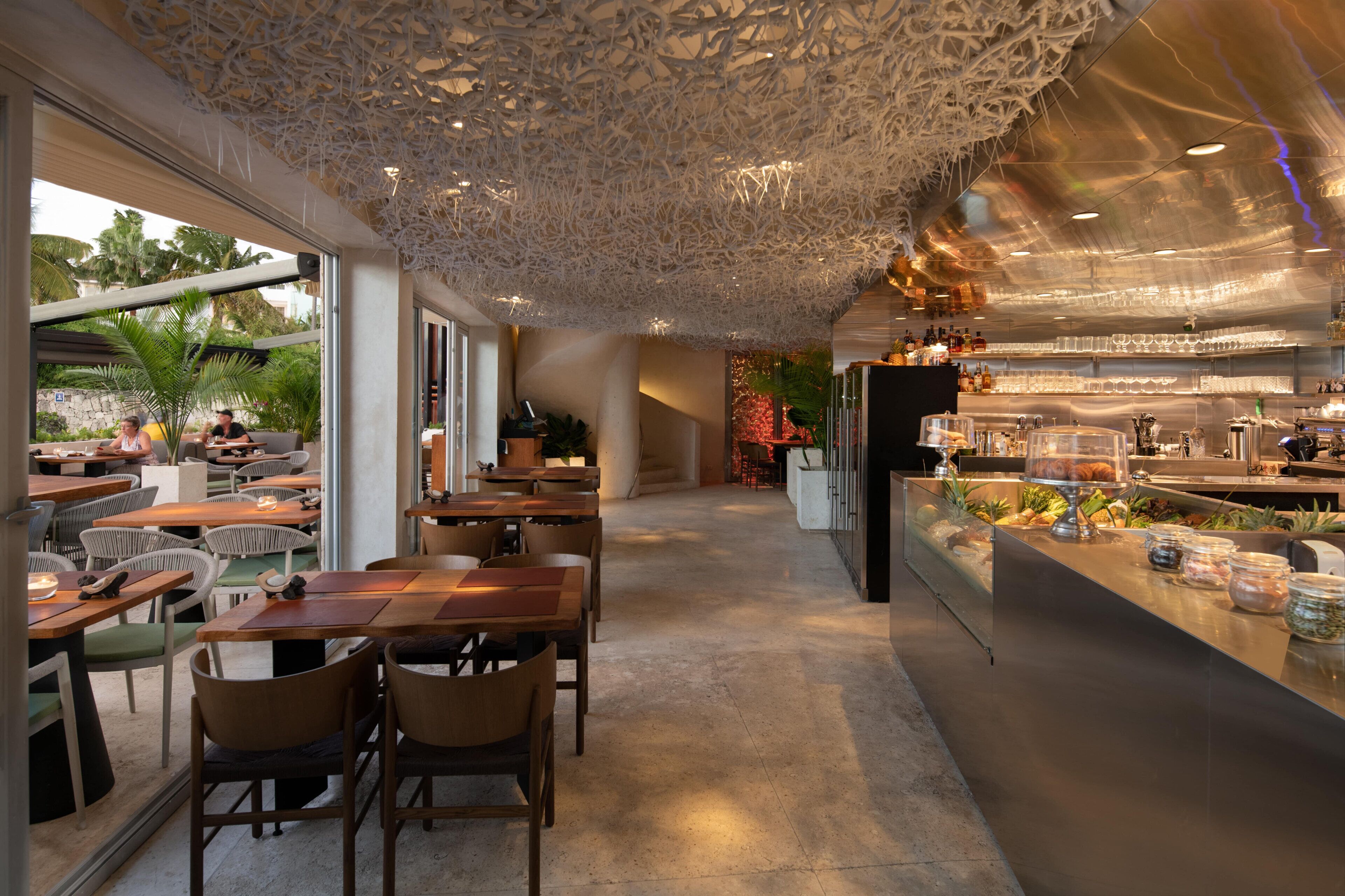 A restaurant with indoor seating, a bar area, and a view of the outdoors.