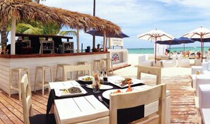 Ein Restaurant direkt am Strand mit Außenbestuhlung, einer Bar und Meerblick.