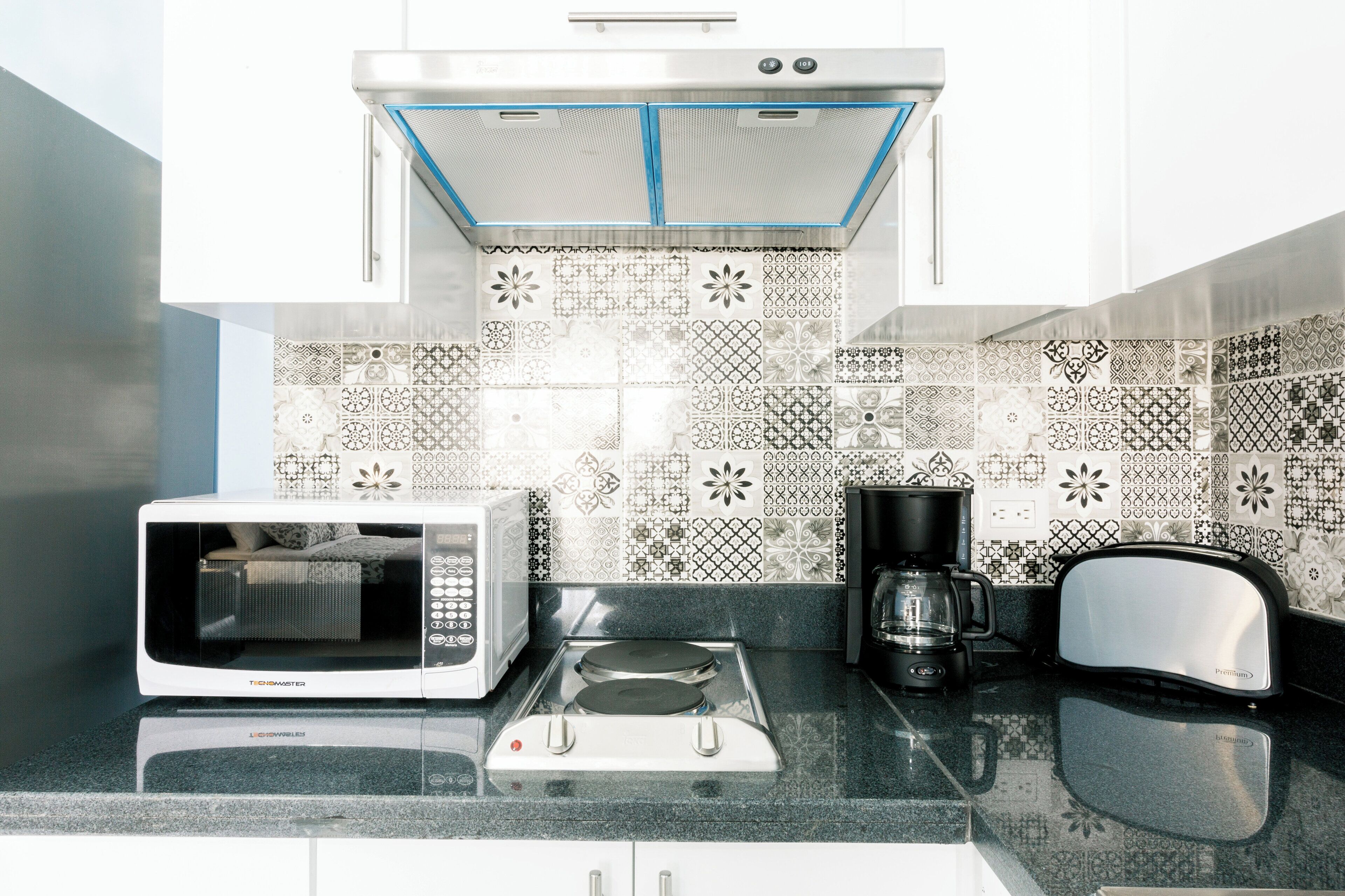 A kitchen with a microwave, toaster, and coffee maker on a granite countertop.