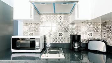 A kitchen with a microwave, toaster, and coffee maker on a granite countertop.
