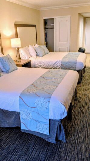 A hotel room with two beds, a nightstand with a lamp, a closet, and a door leading to another room. - Myrtle Beach ocean view condo, full kitchen, pools & hot tubs (Myrtle Beach)