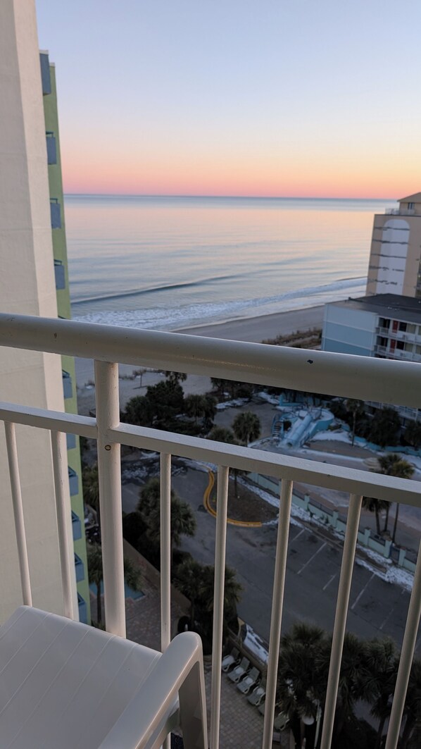 A balcony with a view of a beach and a parking area. - Myrtle Beach ocean view condo, full kitchen, pools & hot tubs (Myrtle Beach)