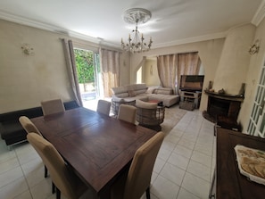Un coin repas avec une table et des chaises en bois, un canapé, un téléviseur et une cheminée.