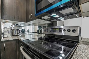 Una cocina con estufa de acero inoxidable, microondas y cafetera.