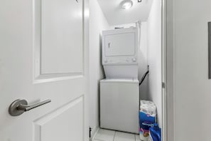 Ein Waschraum mit Waschmaschine, Trockner und einem Stapel Toilettenpapier.