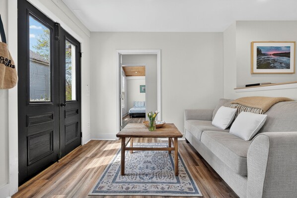 Ein Wohnzimmer mit grauem Sofa, einem Holztisch und einem gemusterten Teppich.