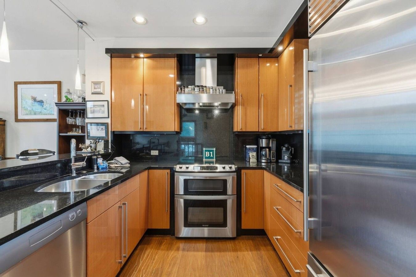 A modern kitchen with stainless steel appliances, wooden cabinets, and a black countertop.
