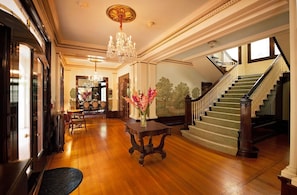 Un hall imponente con candelabro, una escalera y un comedor.