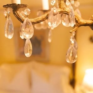 Un candelabro con múltiples gotas de cristal transparente suspendidas de una estructura dorada.