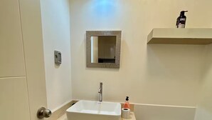 Ein Badezimmer mit Waschbecken, Spiegel, Toilette und Ablagefläche mit einer Flasche.
