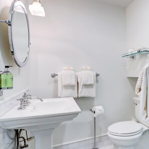 A bathroom with a sink, mirror, toilet, and towel rack.