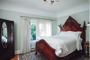 A bedroom with a wooden bed, a dresser, a mirror, and a window with curtains.