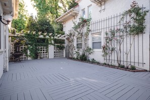Ein Innenhof mit Holzterrasse, weißen Wänden und Kletterpflanzen.