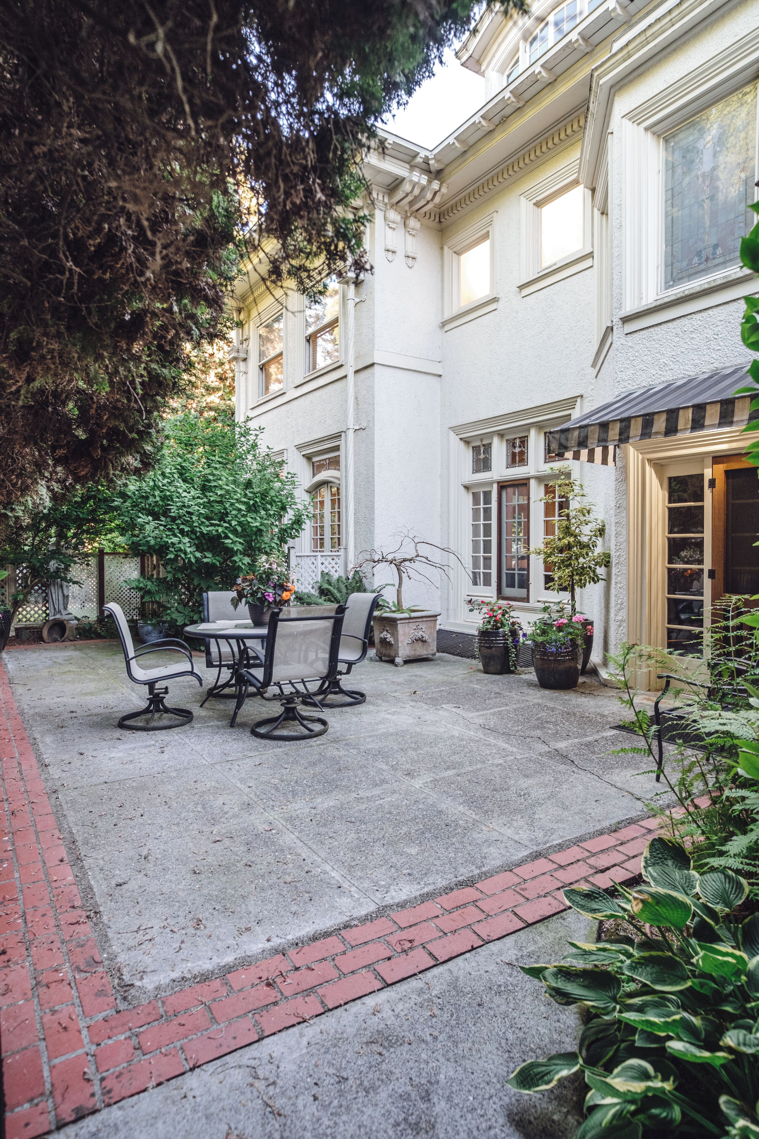 A courtyard with a seating area, potted plants, and a building with large windows.