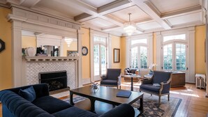 A spacious living room with a fireplace, comfortable seating, and large windows.