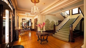 A grand foyer with a chandelier, a staircase, and a dining area.