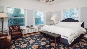 A bedroom with a large bed, a chair, a radiator, and a chandelier.