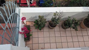 En fliseterrasse med plantekasser og gelænder af metal.