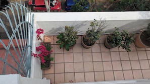 Eine mit Fliesen ausgelegte Terrasse mit Topfpflanzen und einem Metallgeländer.