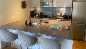 Una cocina moderna con una isla central, electrodomésticos de acero inoxidable y un reloj en la pared.