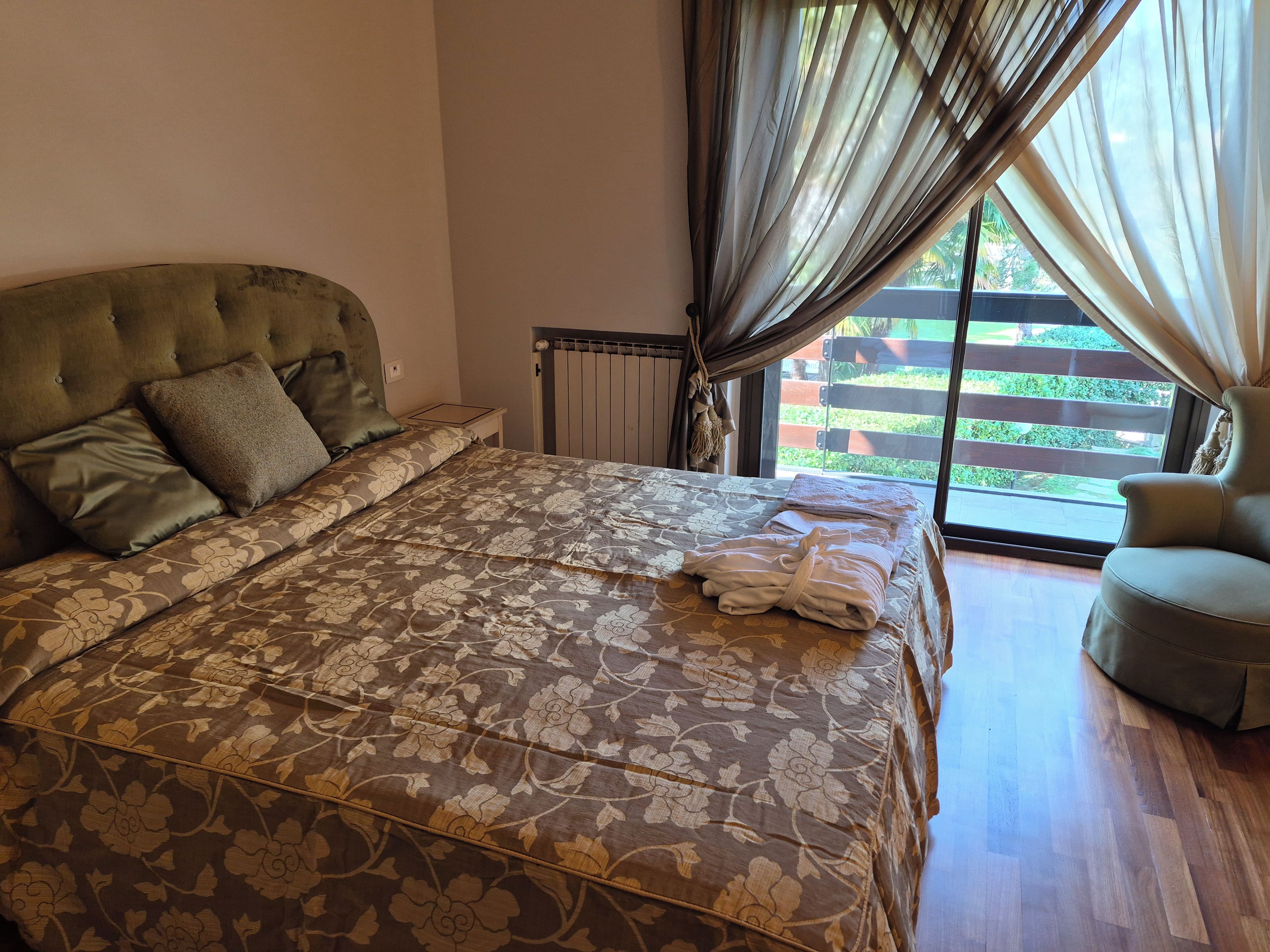 Un lit avec une couvre-lit à motifs floraux, une table de chevet et une chaise.