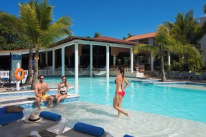 A pool area with lounge chairs, a covered seating area, and palm trees. - Beautiful 1-bdrm suite steps from the beach in Puerto Plata with deck and AC (Puerto Plata)