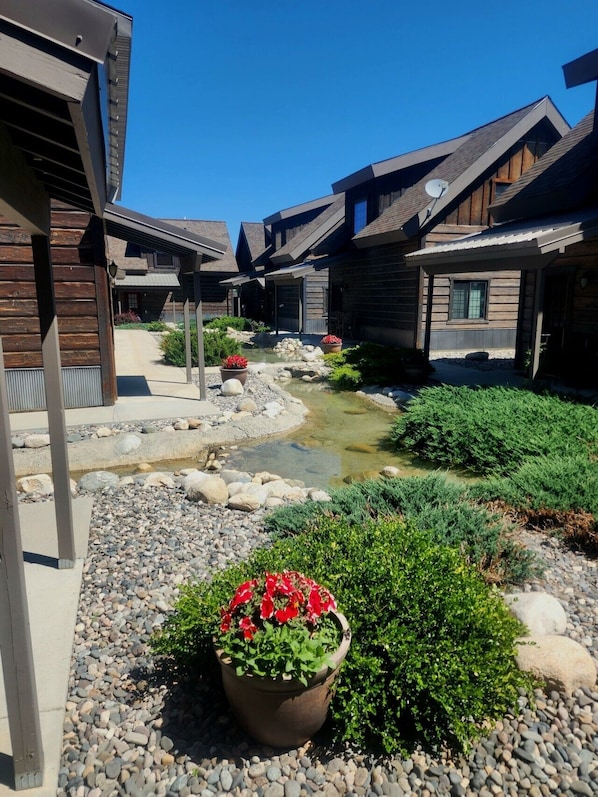 A wooden cabin-style building with a small stream and potted plants.