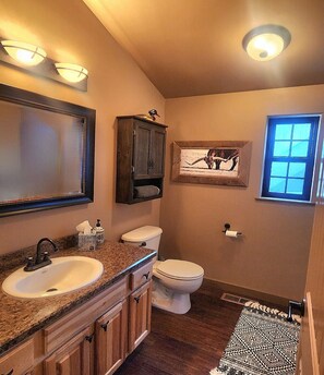 Un baño con lavabo, inodoro, tocador y ventana.