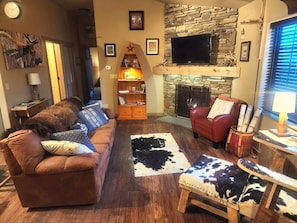 A living room with a stone fireplace, a television mounted above it, and a red armchair.