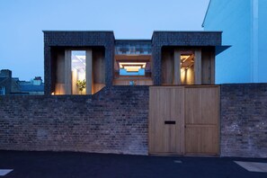 A modern building with a brick facade, large windows, and a wooden door. - Southwark Brick House - Bermondsey London (London)