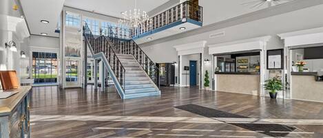 A spacious lobby with a central staircase, a reception desk, and a view of the outdoors.